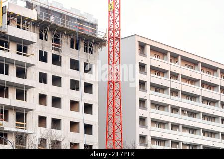 Wohnungsbaukonzept, generischer Wohnblock im Bau, unvollendetes Apartmentgebäude neben einem brandneuen fertigen, zwei verschiedene Stockfoto