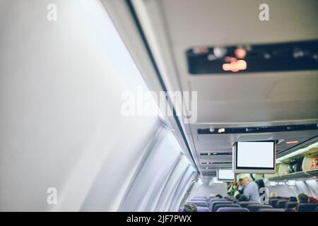 Bild des Flugzeugscreengeräts für Unterhaltung für den Passagier zuschneiden. Fliegen mit dem Flugzeug. Reisekonzept. Stockfoto