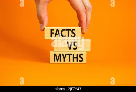 Fakten vs Mythen Symbol. Konzept Worte Fakten vs Mythen auf Holzblöcken auf einem schönen orangenen Tisch orangenen Hintergrund. Geschäftsmann Hand. Business, Finaci Stockfoto