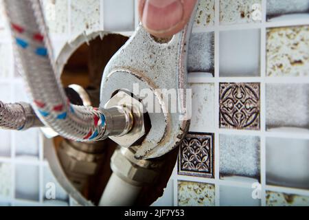 Sanitär-Zubehör, geflochten Edelstahl-Schlauch-Anschluss Wasserrohr für die Lieferung von heißem und kaltem Wasser nach Hause kommt aus dem Loch in der Wand des Hauses in Stockfoto