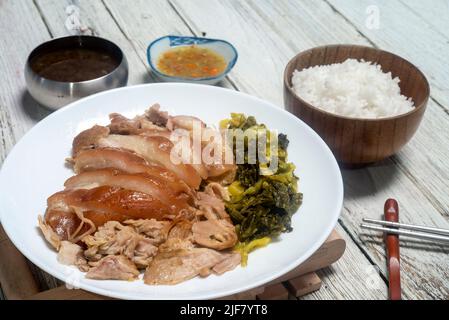 Geschmortes Schweinekeule mit eingelegtem Senf. Gekochte Schweinshaxe mit chinesischen Kräutern. Serviert mit Thai-Stil eingelegten Chilis in Essig Stockfoto