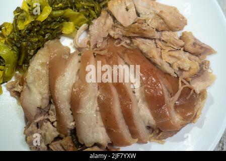 Geschmortes Schweinekeule mit eingelegtem Senf. Gekochte Schweinshaxe mit chinesischen Kräutern. Serviert mit Thai-Stil eingelegten Chilis in Essig Stockfoto