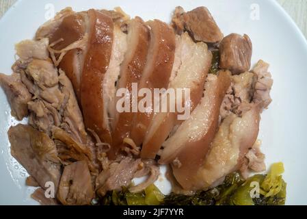 Geschmortes Schweinekeule mit eingelegtem Senf. Gekochte Schweinshaxe mit chinesischen Kräutern. Serviert mit Thai-Stil eingelegten Chilis in Essig Stockfoto