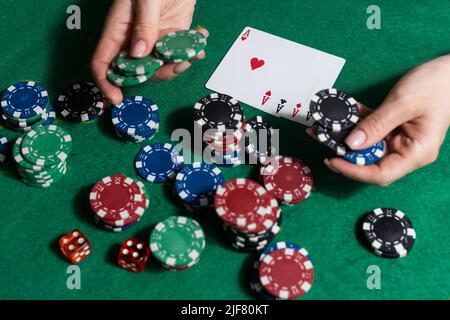 Eine Frau spielt in einem Casino. Öffnen von Karten, um Wetten zu erhöhen. Vor dem Hintergrund von Chips. Poker-Sieg Stockfoto