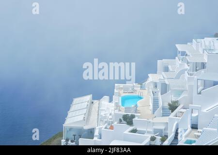 Atemberaubende Villa mit Swimmingpool im typischen weißgetünchten kykladischen Stil mit Blick auf die neblige Ägäis in Imerovigli Santorini Stockfoto