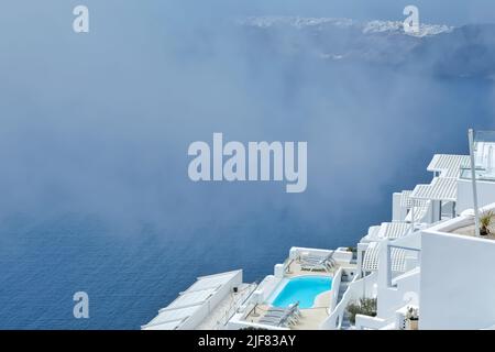 Atemberaubende Villa mit Swimmingpool im typischen weißgetünchten kykladischen Stil mit Blick auf die neblige Ägäis in Imerovigli Santorini Stockfoto