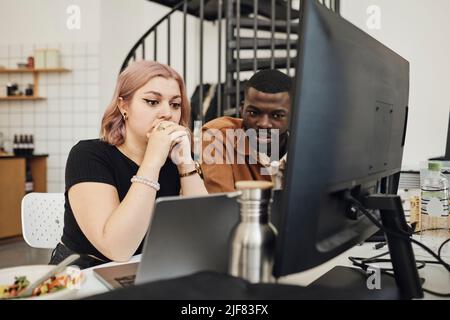 Männliche und weibliche Computerprogrammiererinnen, die im Büro einen Laptop betrachten Stockfoto