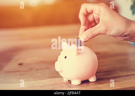 Frau legt Münzen an Sparkasse und Kreditkrise Geld sparen ist der Schlüssel zur finanziellen Unabhängigkeit Stockfoto