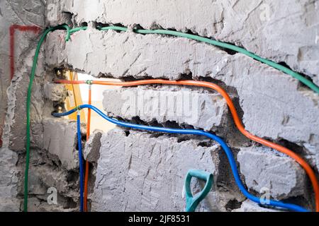 Renovierung und Vorbereitung der Kommunikation in der Wohnung. Installation eines Wassersystems und einer elektrischen Verkabelung in einer Betonwand mit Hilfe eines Korrugates Stockfoto