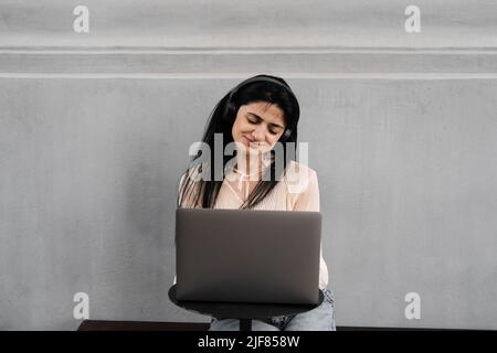 Attraktive dj-Frau mit Laptop und Kopfhörern, die Musik mischt und neue Kompositionen hört. Adorable georgischen Mädchen genießen ihr Leben mit Musik hören Stockfoto