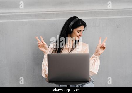 Attraktive dj-Frau mit Laptop und Kopfhörern, die Musik mischt und neue Kompositionen hört. Adorable georgischen Mädchen genießen ihr Leben mit Musik hören Stockfoto