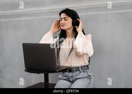 Attraktive dj-Frau mit Laptop und Kopfhörern, die Musik mischt und neue Kompositionen hört. Adorable georgischen Mädchen genießen ihr Leben mit Musik hören Stockfoto