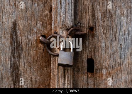 Altes Vorhängeschloss mit Kettenschloss, alte Holztür. Stockfoto
