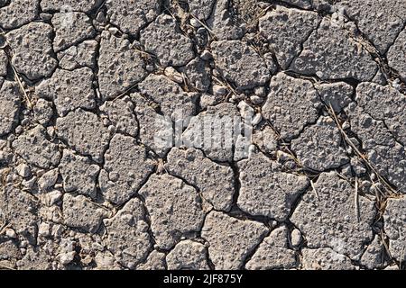 Nahaufnahme von rissiger Asphaltstruktur. Risse auf der alten Fahrbahnoberfläche. Stockfoto