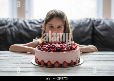 Kleine Mädchen Geburtstagstorte.Home Kuchen mit Beeren gemacht. Kuchen mit Erdbeere, Brombeere, Heidelbeere und Himbeere auf dem Tisch Stockfoto