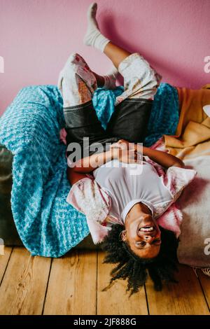 Fröhliche Hipster-Frau, die zu Hause auf dem Sofa liegt Stockfoto