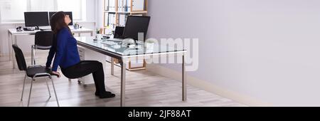 Seitenansicht einer jungen Frau zu tun Stretching Übung im Büro Stockfoto