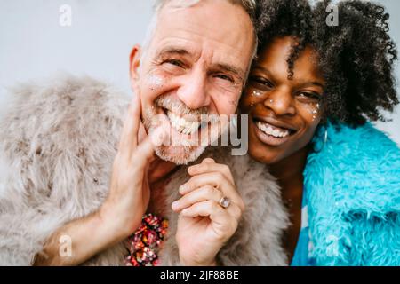 Porträt einer lächelnden Frau und eines schwulen Mannes mit glänzendem Blusher auf den Gesichtern zu Hause Stockfoto