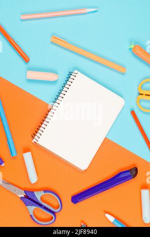 Blaue und orangefarbene Schulpapiere auf Papierhintergrund. Vorräte für das Studium in der Schule. Flatlay, Modell. Rahmen aus buntem Papeterie. Zurück zu scho Stockfoto