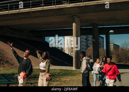 Multirassischer junger Mann und Frau singen, während Freunde an einem sonnigen Tag in der Stadt spazieren Stockfoto
