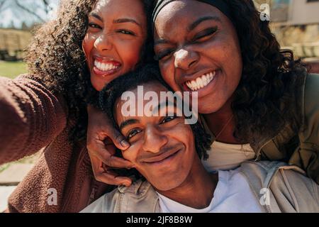 Glückliche junge Freunde, die Gesichter beim gemeinsamen Selfie machen Stockfoto