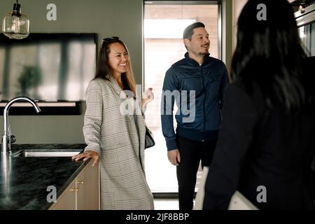 Paar im Gespräch mit Immobilienmakler bei neuem Zuhause Stockfoto