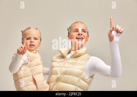 Virtuelle Technologie. Glücklich erfreut nettes Mädchen lächelnd und Blick auf die Kamera, während Mutter in ihren Armen in digitalen virtuellen Brille auf der Bienge hält Stockfoto