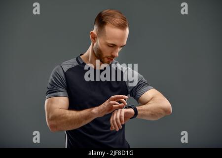 Porträt eines Sportlers, der nach dem Training im Fitnessstudio die Herzfrequenz auf dem Fitness-Trekker überprüft Stockfoto