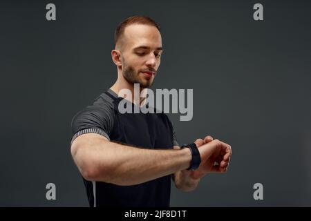 Porträt eines Sportlers, der nach dem Training im Fitnessstudio die Herzfrequenz auf dem Fitness-Trekker überprüft Stockfoto
