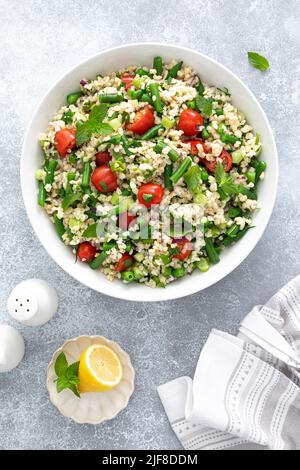 Salat aus Tabbouleh. Tabouli-Salat mit frischer Petersilie, Zwiebeln, Tomaten, Bulgur und grünen Bohnen. Gesunde vegetarische Lebensmittel, Ernährung Stockfoto