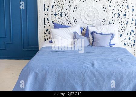 Wunderschönes, klassisches, sauberes, luxuriöses Schlafzimmer in Weiß und Dunkelblau mit Kingsize-Bett und schicken geschnitzten Möbeln. Helles, modernes, stilvolles Schlafzimmer und Wohnzimmer im minimalistischen Stil Stockfoto