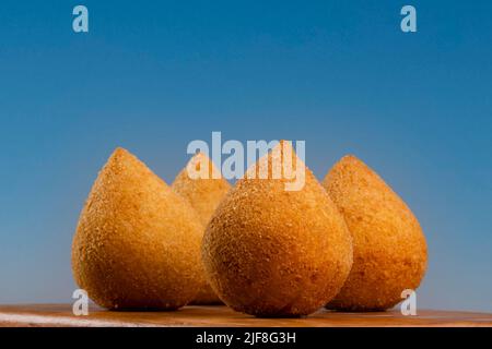 Traditionelle frittierte Coxinha auf Holzbrett auf blauem Hintergrund. Stockfoto