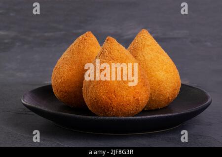 Traditioneller gebratener Coxinha auf einem schwarzen Teller auf Schiefergrund - brasilianischer Snack. Stockfoto