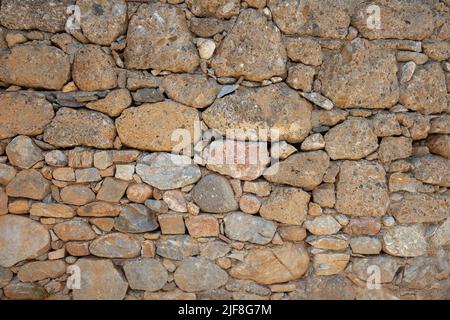 Eine alte Steinmauer aus verschiedenen Steinarten. Steinmauer Hintergrund. Nahaufnahme und Vorderansicht. Stockfoto