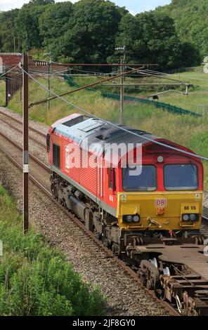 DB Cargo liveried Klasse 66 Elektro-Motor Diesel 66115 vorbei Woodacre bei Garstang an der West Coast Main Line, Lancashire mit Fracht 30.. Juni 2022. Stockfoto