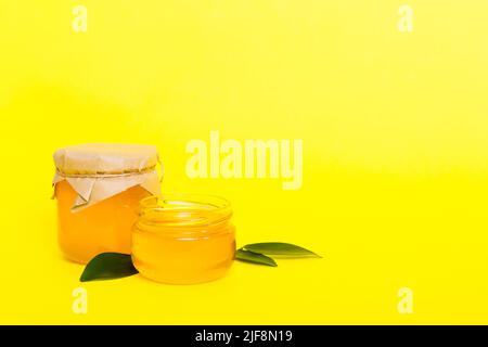 Honig im Glas mit Blättern und Honigtaube auf farbigem Hintergrund Draufsicht mit Text kopieren. Stockfoto