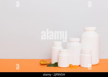 Omega-3 Kapseln liegen in einer weißen Flasche auf einem Tisch mit grünem Blatthintergrund. Fischöltabletten. Biologisch aktive Zusatzstoffe. omega 6, Omega 9, Vitam Stockfoto