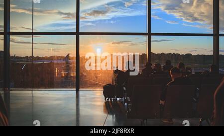 Leere Stühle in der Abflughalle des Flughafens. Nicht erkennbare Menschen verschwimmen. Stockfoto