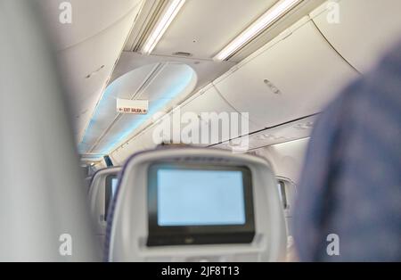 Bild des Flugzeugscreengeräts für Unterhaltung für den Passagier zuschneiden. Fliegen mit dem Flugzeug. Reisekonzept. Selektiver Fokus. Stockfoto