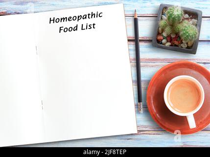 Homöopathischer Text auf leerem Notizbuch, Bleistift und Kaffee auf Holztisch-Hintergrund am Arbeitsplatz. Homöopathisches Therapiekonzept Stockfoto