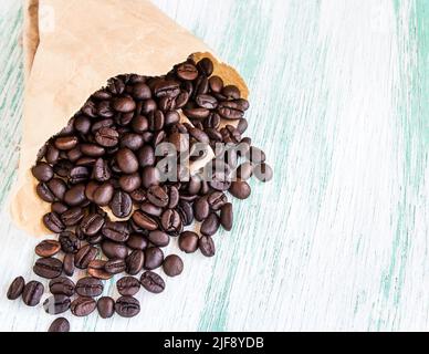 Nahaufnahme geröstete Kaffeebohnen in Papiertüten auf Holzhintergrund Stockfoto