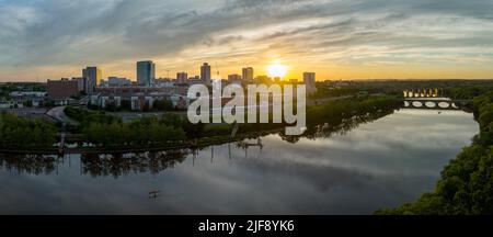 Luftaufnahme der Innenstadt von New Brunswick und der Rutgers University, wenn die Sonne hinter den Hochhäusern untergeht und auf dem Raritan-Fluss reflektiert wird Stockfoto