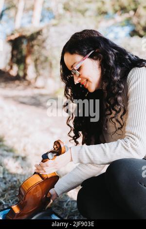 Junge Brünette Frau, die die Geige aus dem Gehäuse nimmt Stockfoto