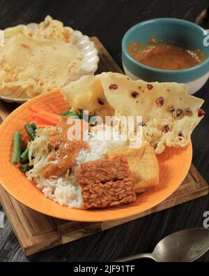 Nasi Pecel, traditionelles indonesisches Menü mit würziger Erdnusssauce, Tempeh, gekochtem Gemüse und gebratenen Tofu, Rempeyek, Beliebt für Frühstück, Abendessen, OP Stockfoto