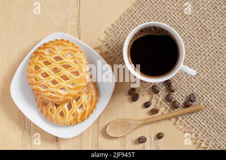 Tasse Kaffee und Kekse mit einem Apfel Füllung in Teller, auf Holzhintergrund, Draufsicht Stockfoto