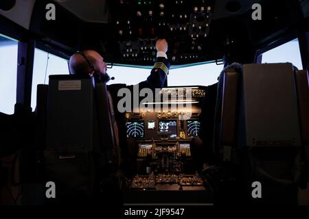 Kapitän und afroamerikanischer Pilot fliegen Flugzeug Jet in der Kabine mit Bedienfeld Power-Schalter und Armaturenbrett Navigationsbefehl im Cockpit. Das Airliner-Team drückt Knöpfe, um das Flugzeug zu fliegen. Stockfoto