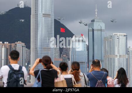 Hongkong, China. 01.. Juli 2022. 1.. Juli, Hongkong. Mitglieder der Öffentlichkeit beobachten, wie die Hubschrauber der Flugdienste der Regierung mit den nationalen und SAR-Flaggen vorbeifliegen und während der Flaggenanhebung auf dem Goldenen Bauhinia-Platz in Wan Chai zum 25.. Jahrestag der Gründung der HKSAR, die von der Tsim Sha Tsui-Promenade aus betrachtet wird, Während die Polizei patrouilliert und Wache steht. 01JUL22 SCMP/Nora Tam Credit: South China Morning Post/Alamy Live News Stockfoto