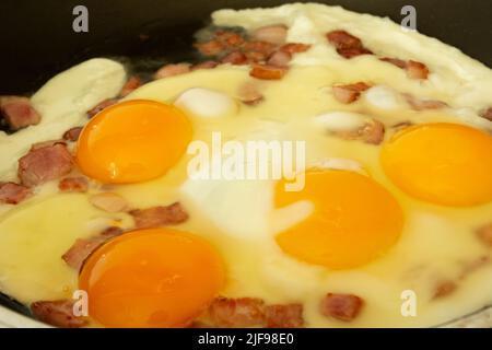 Rühreier mit Speck in einer Pfanne braten Stockfoto