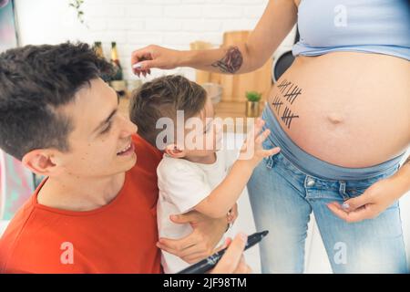 Kleines Kind zählt Wochen seiner Schwangeren Mutter mit Eltern, glückliches Familienkonzept. Hochwertige Fotos Stockfoto