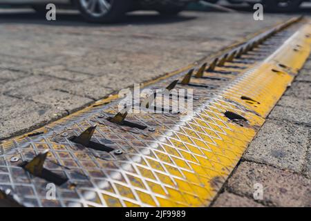 Metallblockade auf der Straße, die die Reifen eines Fahrzeugs durchbricht. Außenaufnahme. Reisebeschränkungen. Hochwertige Fotos Stockfoto